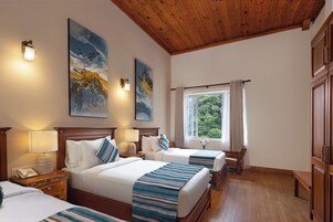 Habitación de hotel con dos camas, techo de madera, ventana con cortinas y obras de arte en las paredes.