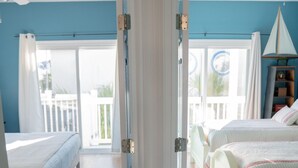 A bedroom with a large sliding door, a bed, a bedside table, and a lamp.