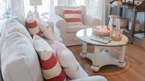 A living room with a sofa, armchairs, a coffee table, and a sailboat decoration.