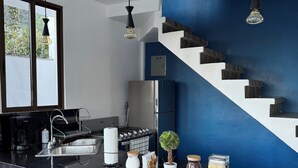 A modern kitchen with a black countertop, stainless steel appliances, and a blue accent wall.