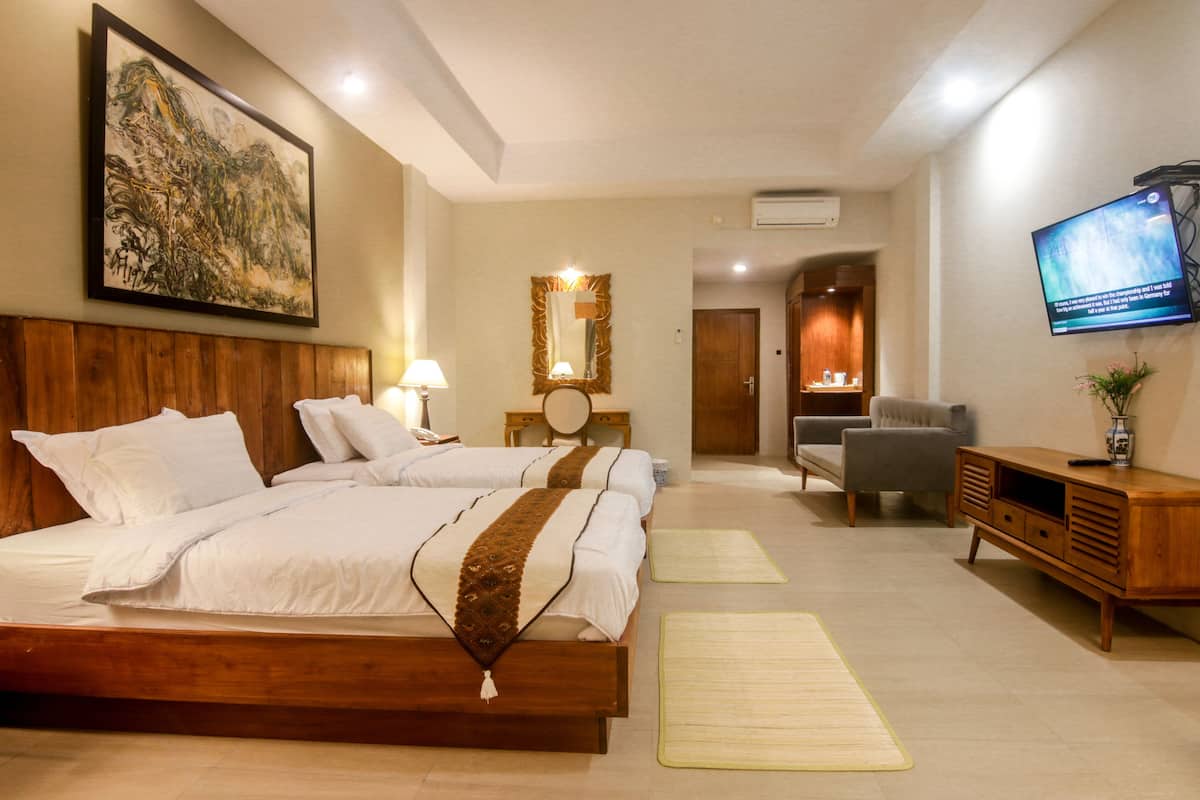 Une chambre d’hôtel avec deux lits, une télévision, un bureau et un miroir.