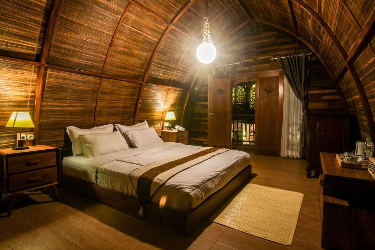 Une chambre confortable avec un grand lit, une tête de lit en bois, des tables de chevet avec des lampes et un plafond en bois.