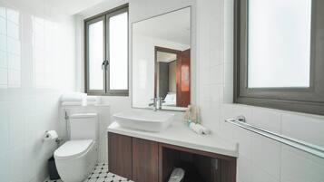 Une salle de bain moderne avec des toilettes blanches, un lavabo rectangulaire et un grand miroir au-dessus.