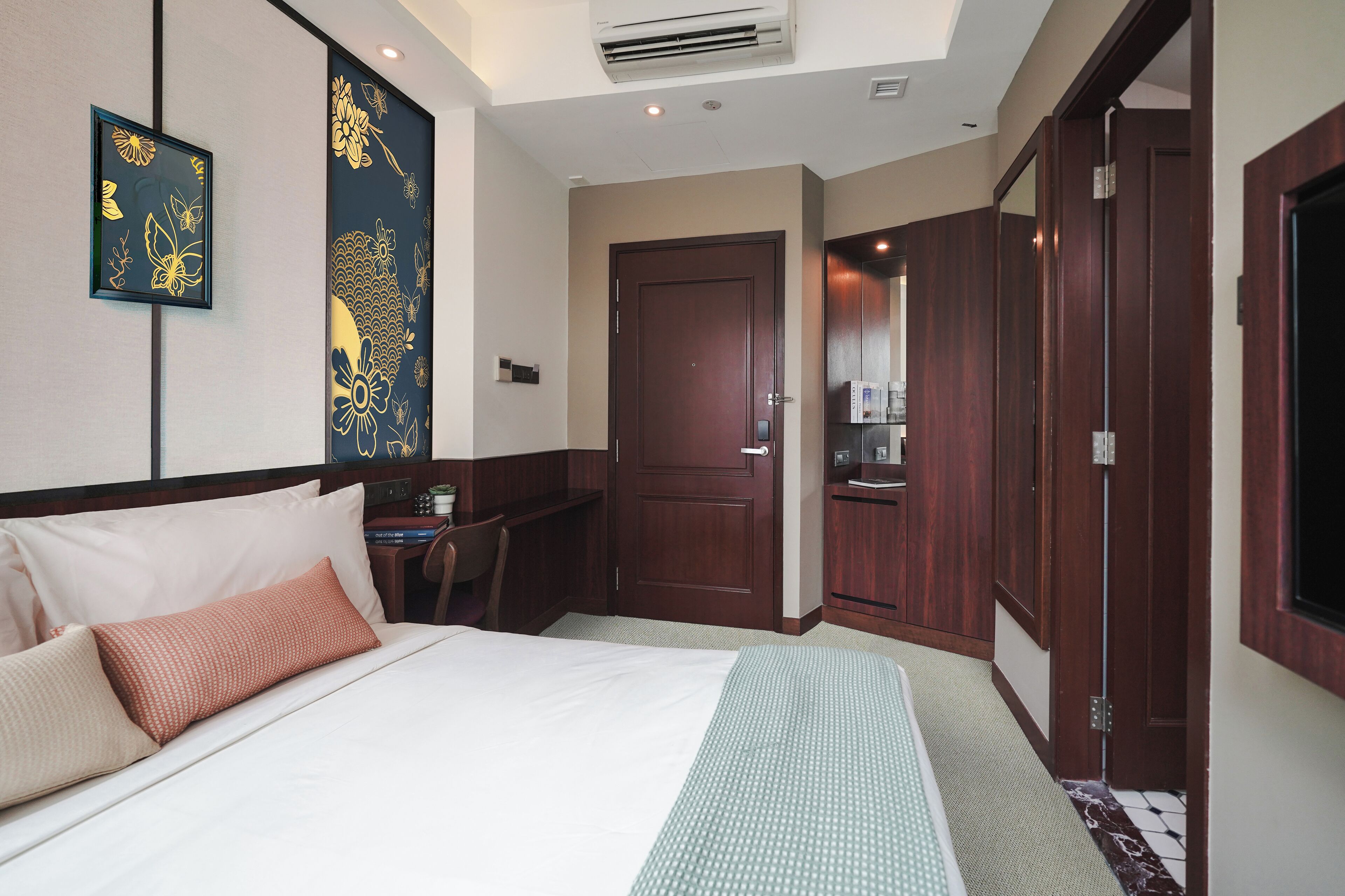 A hotel room with a bed, a desk, and a wardrobe.