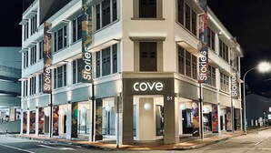 Ein mehrstöckiges Gebäude mit einem gut sichtbaren 'cove' Schild im Erdgeschoss, das mehrere Schaufenster mit 'Stories' Bannern aufweist.