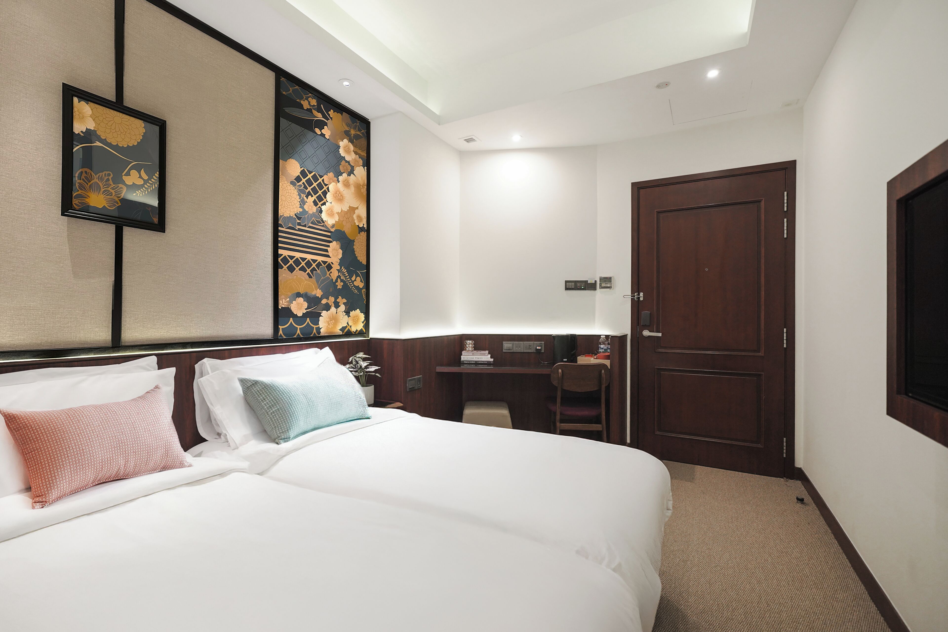 A hotel room with a large bed, a desk, and a wardrobe.