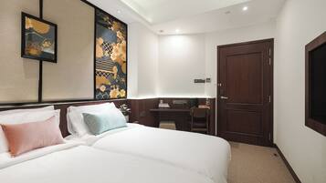 A hotel room with a large bed, a desk, and a wardrobe.
