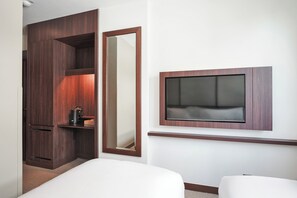 Een hotelkamer met een bed, een aan de muur bevestigde televisie, een kledingkast en een spiegel.