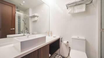 Un baño moderno con un lavamanos grande blanco, un espejo, una ducha y un inodoro.