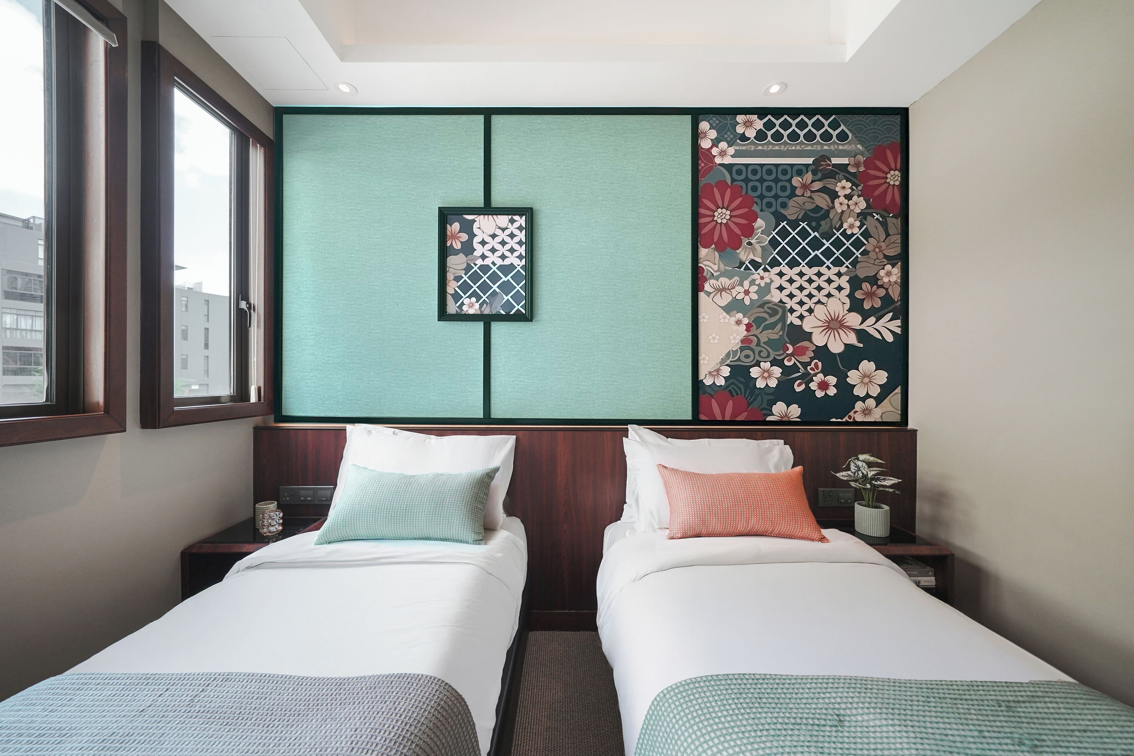 A hotel room with two beds, a large window, and a decorative wall panel.