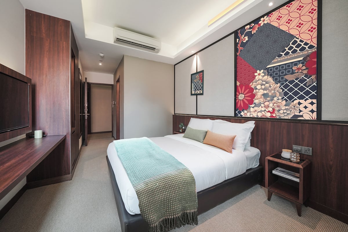Quarto de hotel com cama, mesa de cabeceira e um grande painel decorativo na parede.