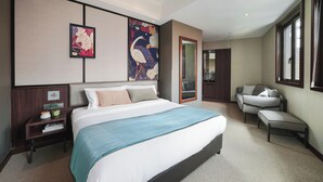 Ein modernes Hotelzimmer mit einem großen Bett, einer Sitzecke mit einem Sessel und einem großen Kunstwerk an der Wand.