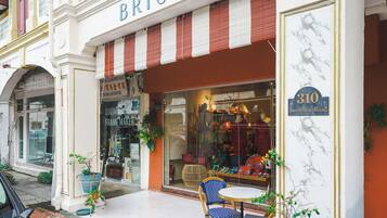 Fachada con el nombre 'BRISA' sobre la entrada, un cartel que indica '310 Joo Chiat Road' y una puerta de cristal con productos a la vista.