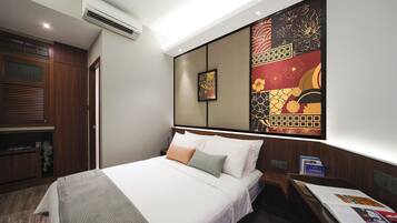 A hotel room with a neatly made bed, a desk with a chair, and a large decorative wall piece.