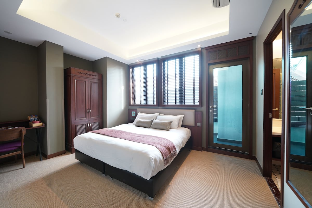 Um quarto com uma cama grande, uma escrivaninha e um guarda-roupa.