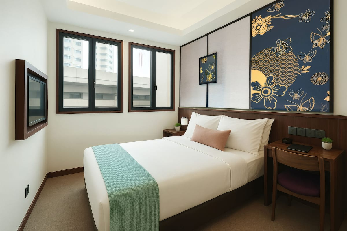 Quarto de hotel com cama, escrivaninha, cadeira, televisão e uma grande obra de arte floral na parede.