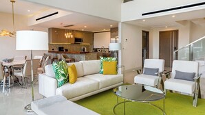 A modern living room with a sofa, chairs, a glass coffee table, and a dining area with chairs and a table. - Enjoy 2026 Christmas Week in a 3-bdm Loft with Rooftop Terrace at Garza Blanca (Cancún)