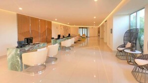 A modern hotel lobby with a reception desk, seating area, and large windows. - Enjoy 2026 Christmas Week in a 3-bdm Loft with Rooftop Terrace at Garza Blanca (Cancún)