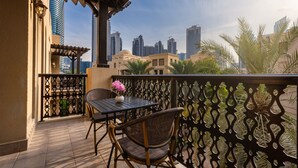A balcony with a table and chair, a decorative fence, and a cityscape view. - Stylish & Spacious Apartment in Downtown Dubai (Dubai)