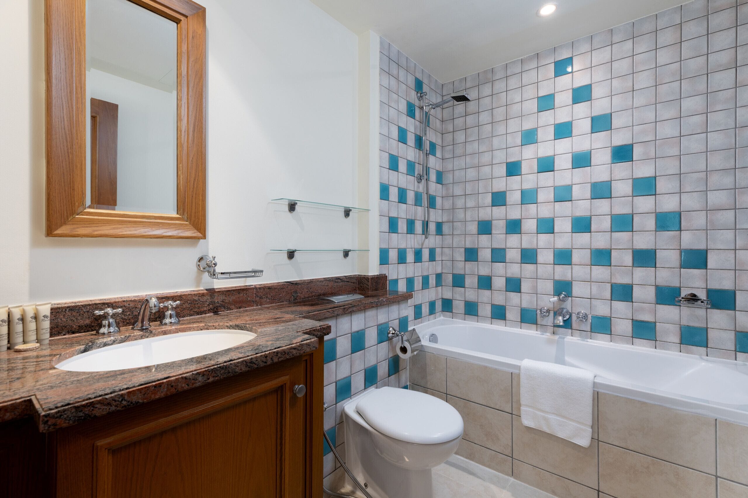 Et badeværelse med vask, spejl, toilet og badekar.