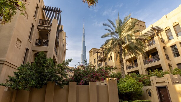A residential area with modern buildings, a prominent skyscraper in the background, and lush greenery. - Stylish & Spacious Apartment in Downtown Dubai (Dubai)