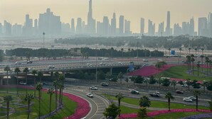 A cityscape with a prominent skyscraper, a highway with vehicles, and landscaped areas with palm trees. - Sunset Haven - Chic Creek Studio (Dubai)