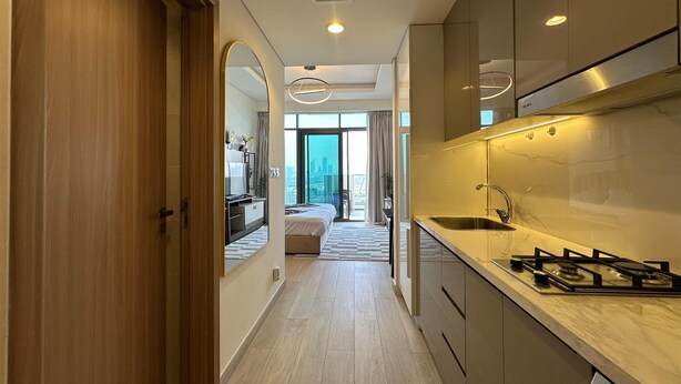A modern hotel room with a kitchen, a large mirror, and a view of the city. - Sunset Haven - Chic Creek Studio (Dubai)