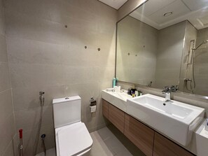 A modern bathroom with a toilet, bidet, and a large mirror above a double sink. - Sunset Haven - Chic Creek Studio (Dubai)