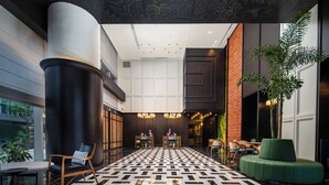 A lobby with a patterned floor, a reception desk, seating areas, and a large column. - UrCove by Hyatt Guangzhou Canton Tower Exhibition Center (Guangzhou)