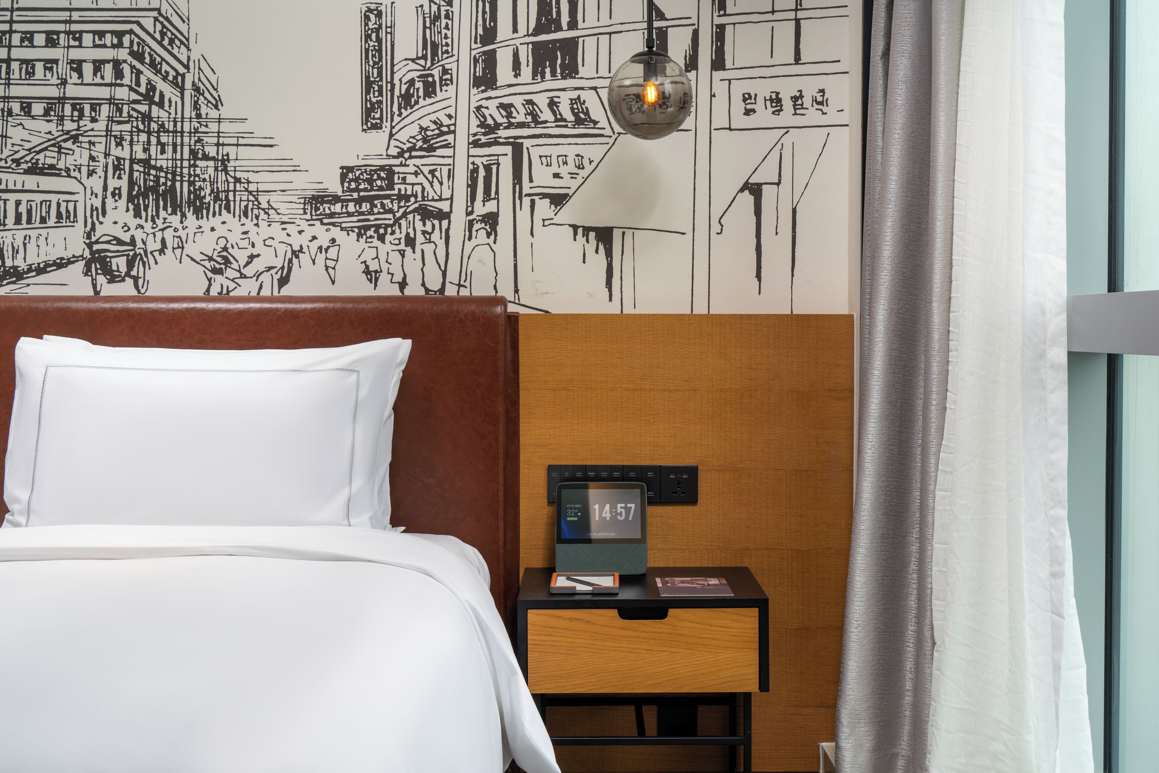 A hotel room with a bed, a nightstand with a clock, a lamp, and a wall mural.