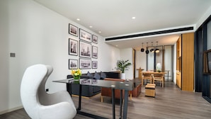 Una sala de estar moderna con una butaca blanca curvada, un sofá negro y un comedor con una mesa y sillas de madera.