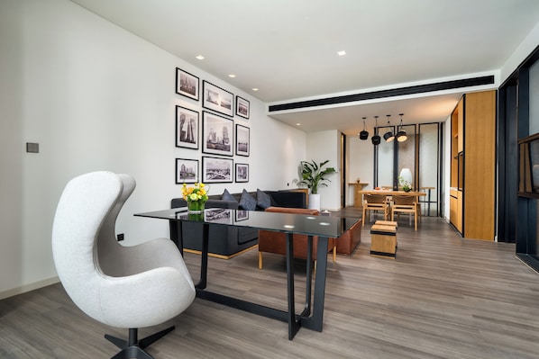 Una sala de estar moderna con una butaca blanca curvada, un sofá negro y un comedor con una mesa y sillas de madera.