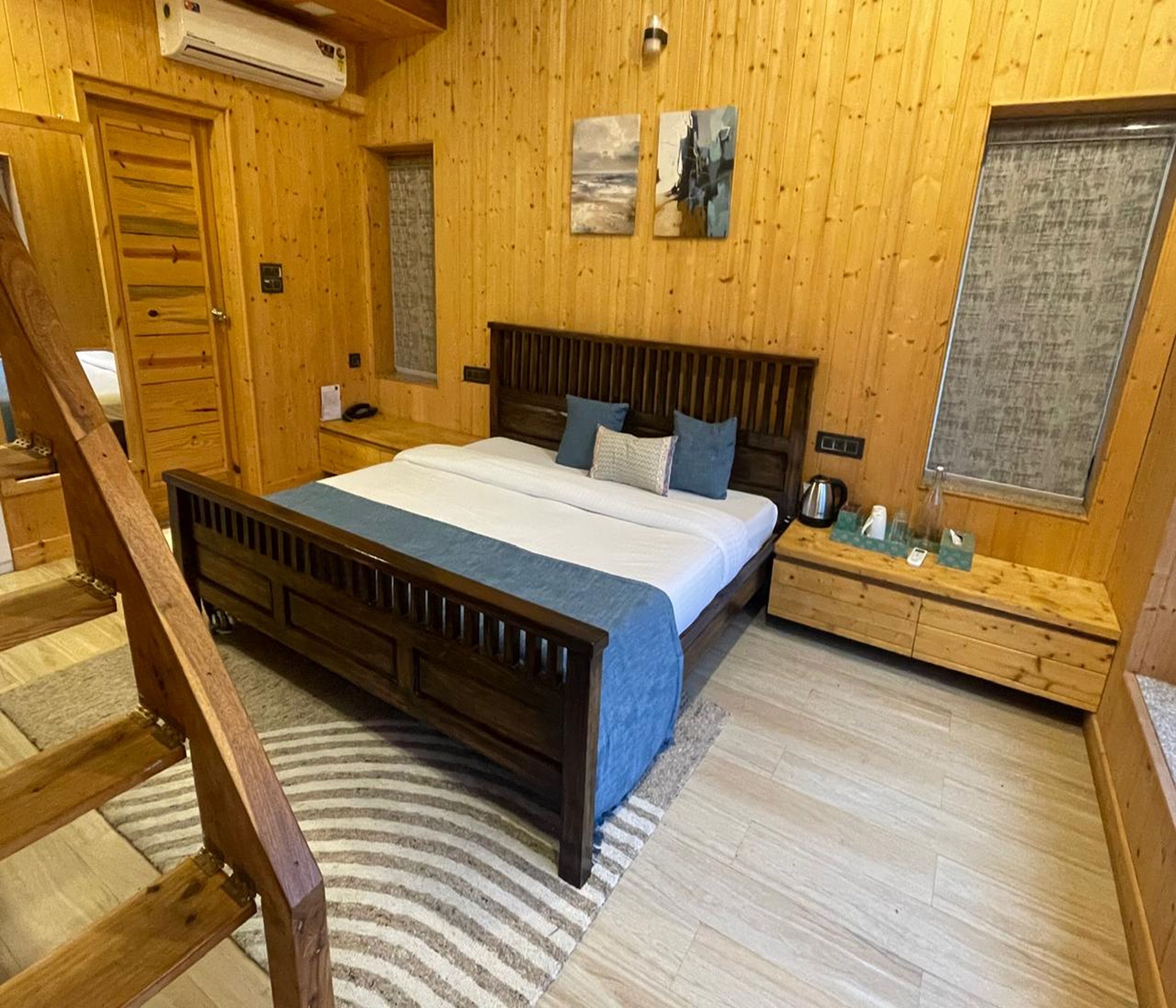 A wooden room with a bed, a wooden dresser, a window, and a door.
