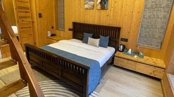 A wooden room with a bed, a wooden dresser, a window, and a door.