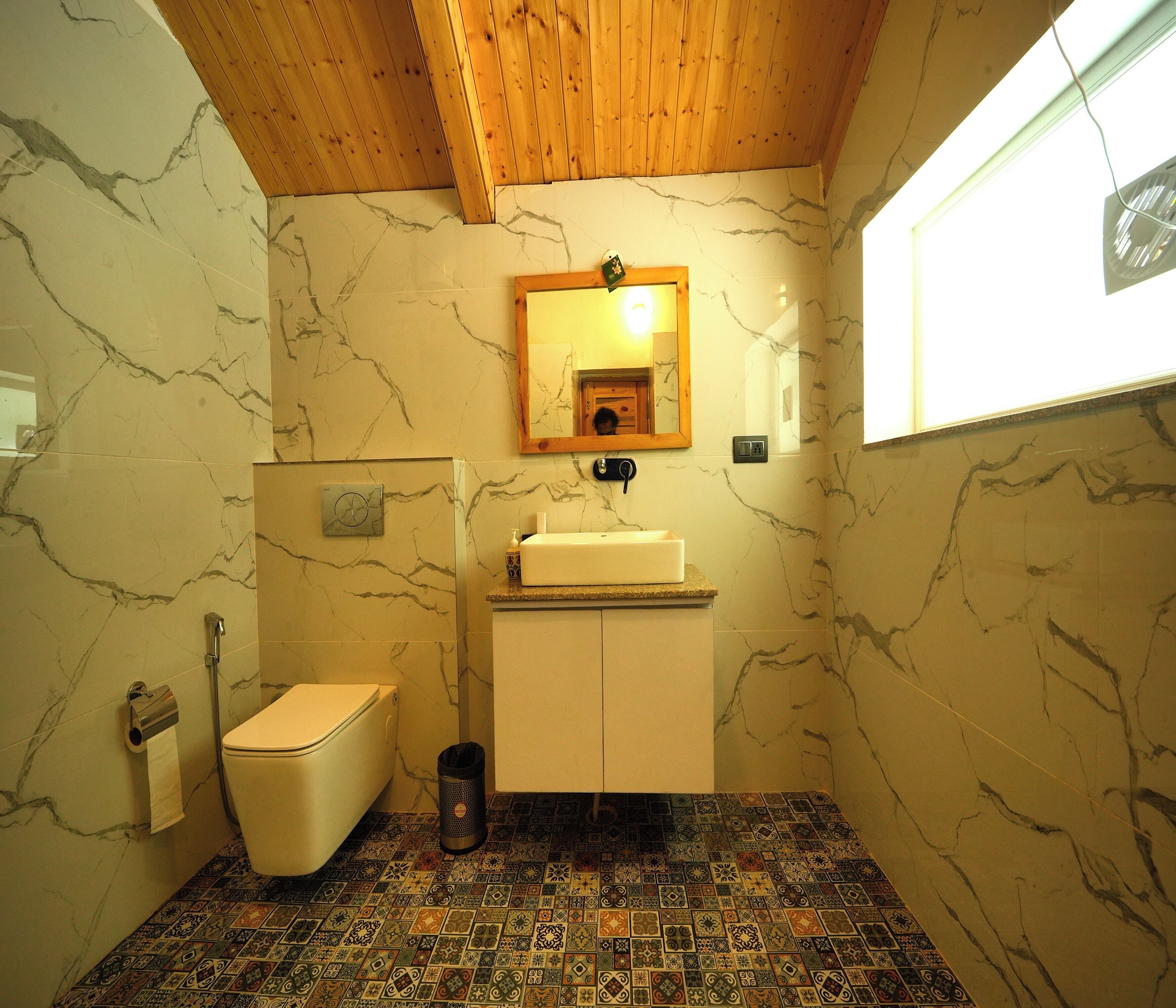 A bathroom with a toilet, sink, and mirror.