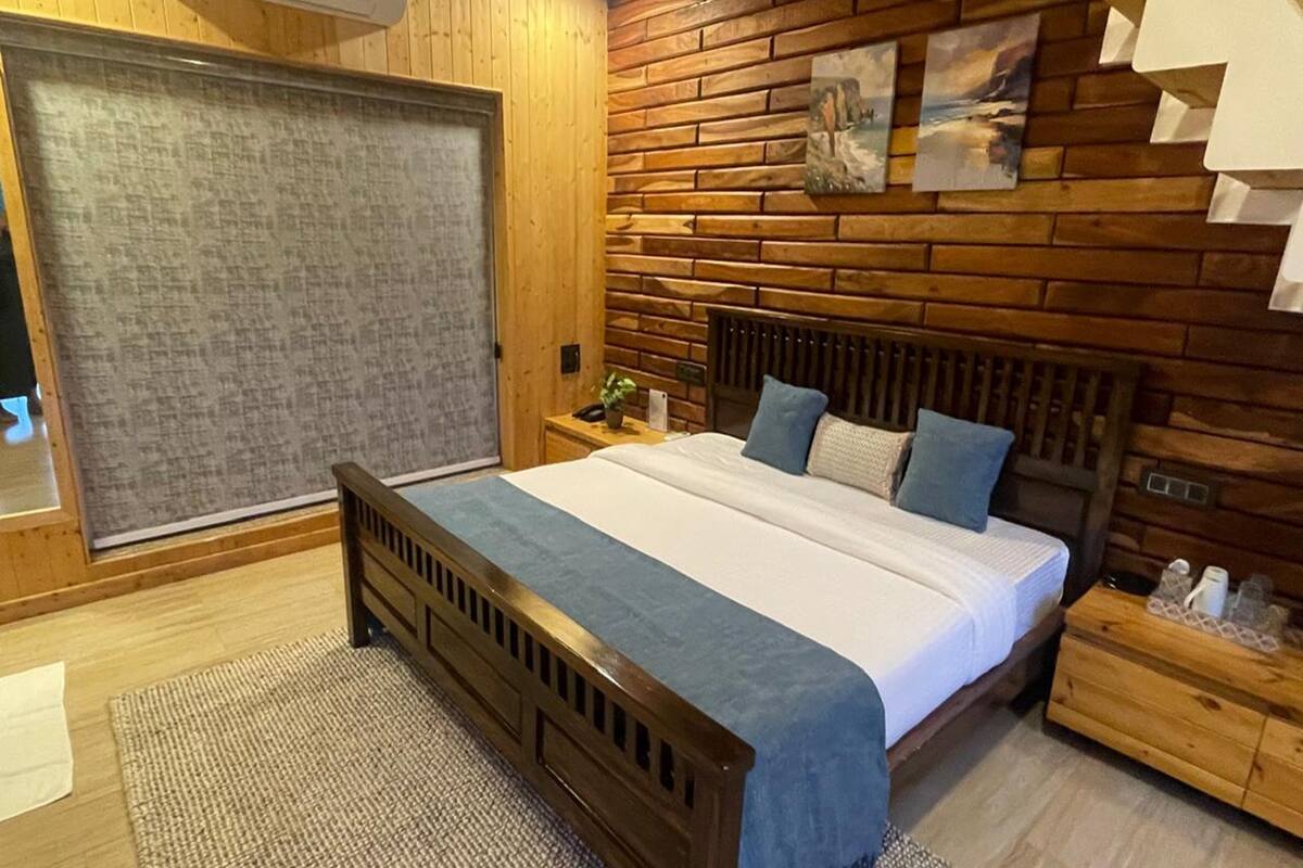A bedroom with a wooden headboard, a large bed, a nightstand, and a wall-mounted air conditioner.