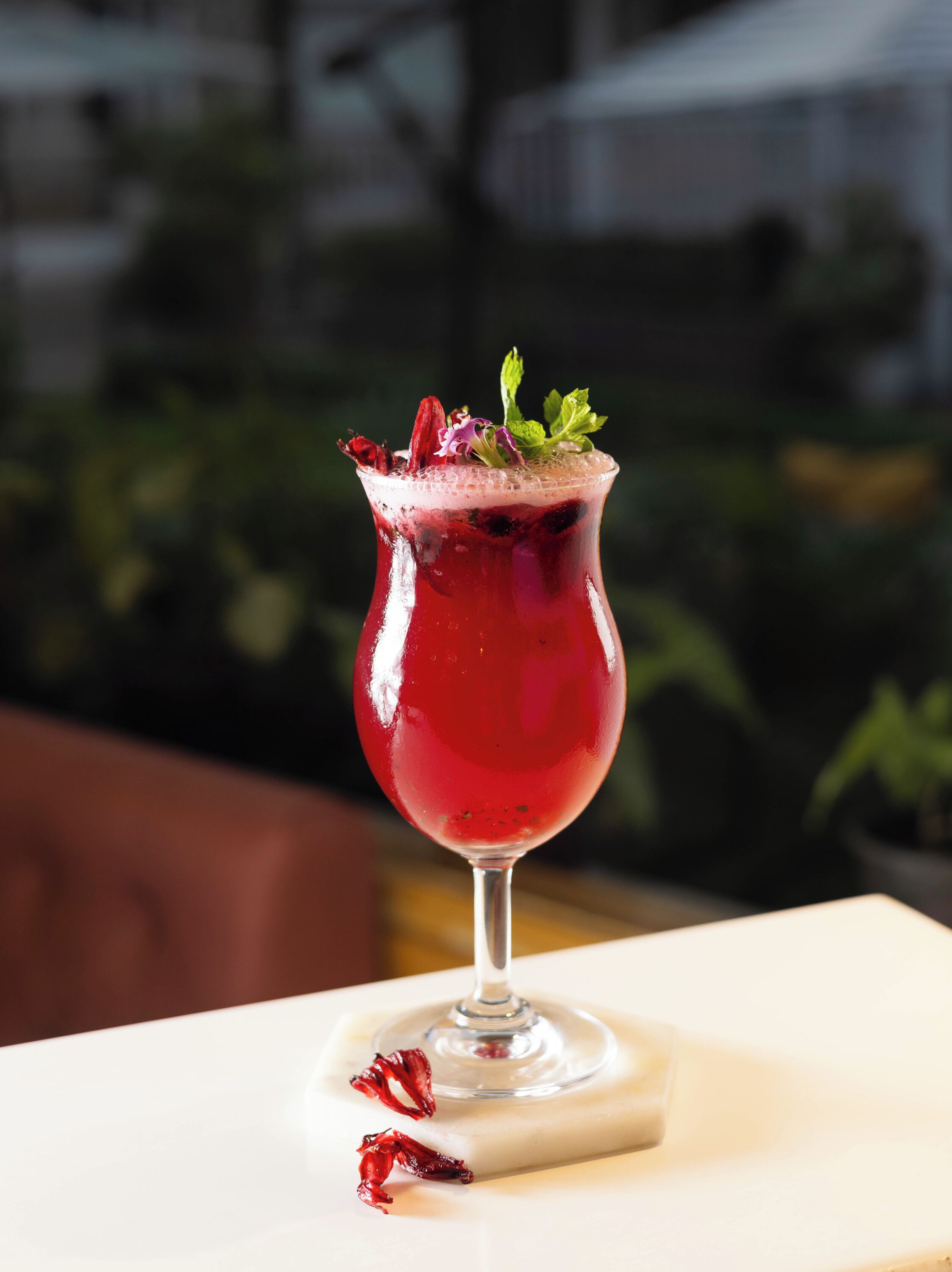 A cocktail in a glass with a stem, placed on a white coaster.