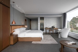 Un dormitorio moderno con una cama grande, un escritorio, una silla y vistas a la montaña.