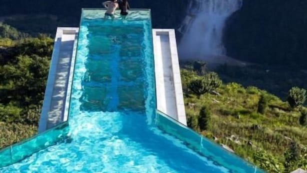 A rectangular infinity pool with two people at the far end, overlooking a waterfall and lush greenery. - YAOJIA WANGPU VILLA (Anshun)