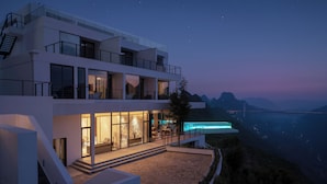 A modern multi-story building with a spacious outdoor area, large windows, and a view of a bridge and mountains. - YAOJIA WANGPU VILLA (Anshun)