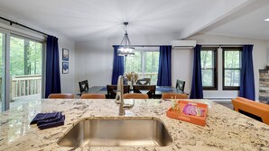 Eine moderne Küche mit Granit Arbeitsplatte, Edelstahl-Spüle und einem Essbereich mit Tisch und Stühlen.