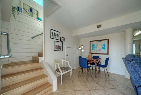 A staircase leading to a landing with a dining area featuring a table, chairs, and a wall-mounted map.