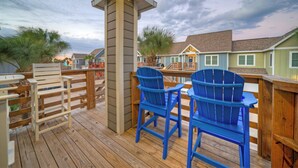 A wooden deck with two blue Adirondack chairs and a white folding chair. - Salty Seas | Shared Pool, Beach Gear & Prime Location Near Port Aransas Beaches (Port Aransas)