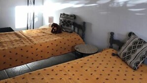 A room with two beds, each with a patterned bedspread, a hanging light fixture, and a wall-mounted sign. - Le Cigalou (Sainte-Croix-du-Verdon)