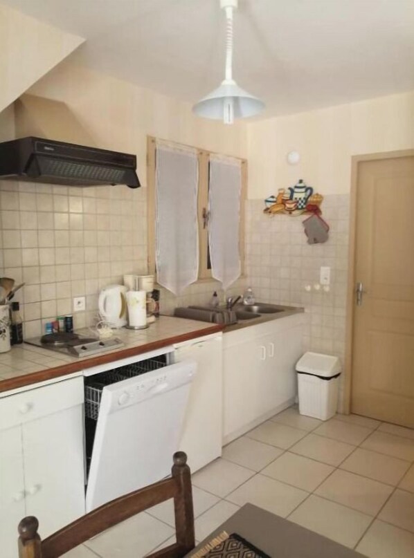 Cocina compacta con armarios blancos, lavavajillas empotrado, un lavabo y un ventilador de techo.