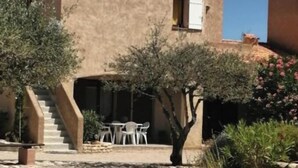 A building with a stucco exterior, a covered outdoor seating area, and a stone staircase leading to the entrance. - Le Cigalou (Sainte-Croix-du-Verdon)