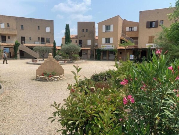 A courtyard with buildings, a central stone structure, and surrounding greenery. - Le Cigalou (Sainte-Croix-du-Verdon)