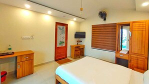 A bedroom with a bed, a desk, a chair, a TV, and a wardrobe. - Mizzle Resort (Vythiri)