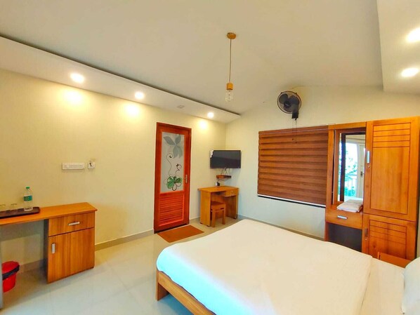 Une chambre à coucher comprenant un lit, un bureau, une chaise, un téléviseur et une armoire.