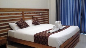 A neatly made bed with a wooden headboard, white bedding, and a brown patterned throw. - Mizzle Resort (Vythiri)